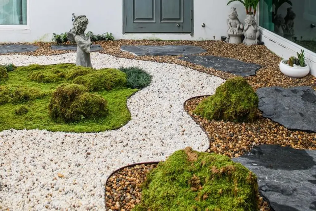 A modern Zen garden featuring raked white gravel waves, lush green moss mounds, and large dark stepping stones.