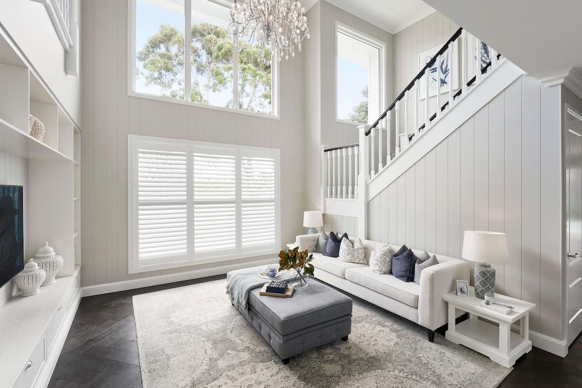 Balanced and simple furniture layout for an upscale Hamptons style home featuring white sofas and navy accents.