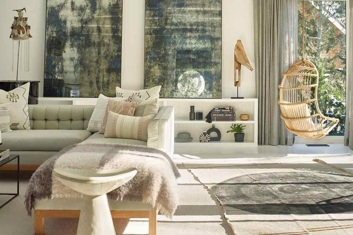 Hamptons style entryway with a rattan armchair, coastal chic jute rug, and a rustic wooden cabinet.