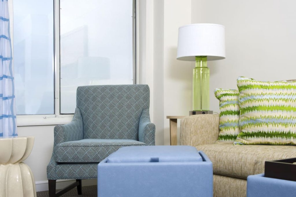 Coastal style table lamp with a green glass base and white drum shade in a breezy Hamptons living room