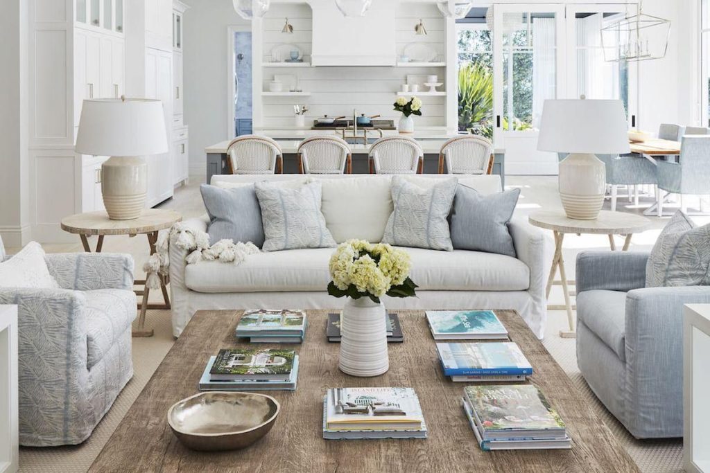 Modern Hamptons style living room with a solid white wash wood coffee table, textured boucle sofa, and blue coastal wall art with ocean views.